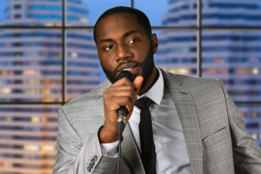 Siyah adam mikrofona konuşur.