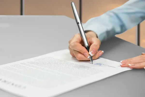 Young ladys hand signing document. — Stockfoto
