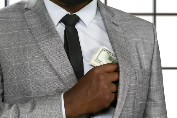 Afro businessman hides money. — Stock Photo, Image