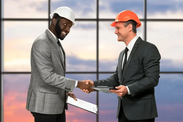 Businessmen in hardhats shaking hands. — Stock Photo, Image