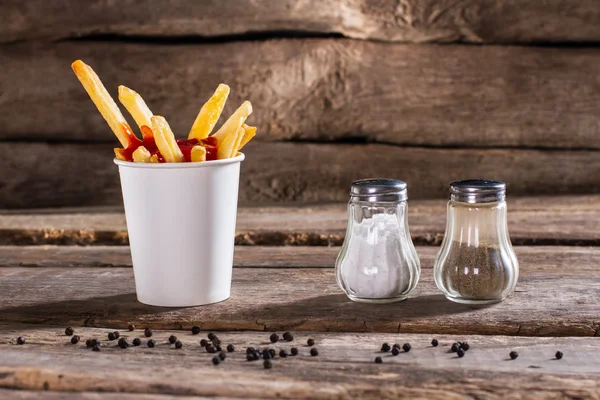 Xícara de batatas fritas com caixa de pimenta . — Fotografia de Stock