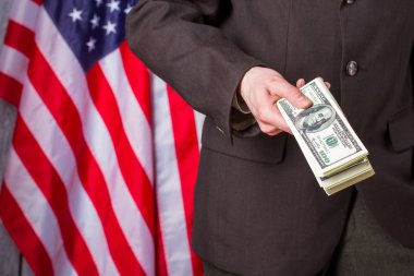 Bayrağın yanında dolar tutan işadamı.