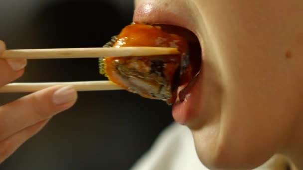 Жінка з паличками їсть суші . — стокове відео