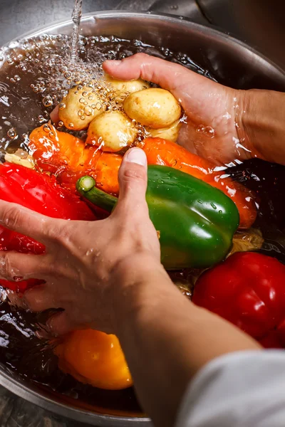 Ruce umýt brambory a papriku. — Stock fotografie