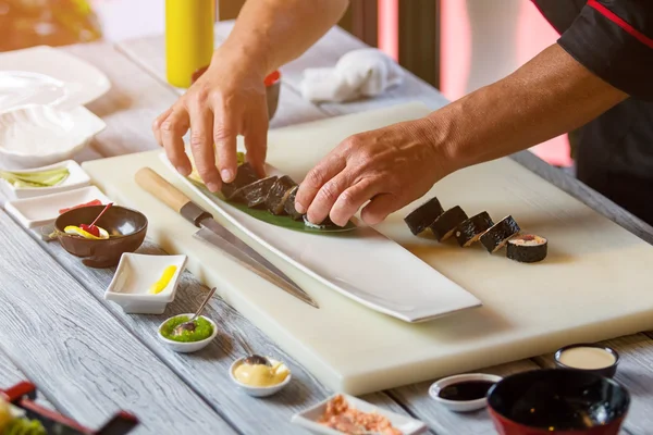 Mannelijke handen aanraken sushi rolls. — Stockfoto