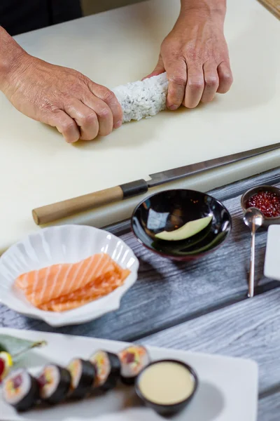 Ман рука коснется суши ролл. — стоковое фото