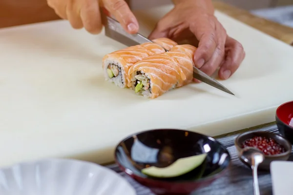 Knife cuts sushi rolls. — Stock Photo, Image