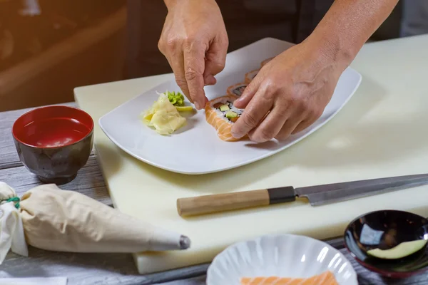 Mannelijke handen aanraken sushi rolls. — Stockfoto