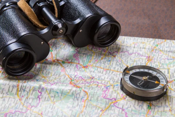 Binoculars and compass on map.
