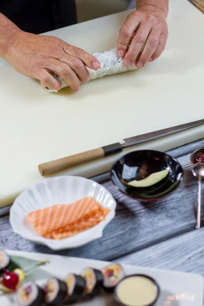 Руки-манипуляторы прикасаются к роллу суши . — стоковое фото