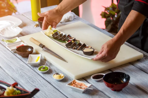 Handen houden plaat met sushi. — Stockfoto