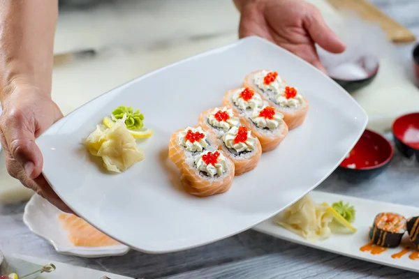 Las manos sostienen el plato con sushi . — Foto de Stock