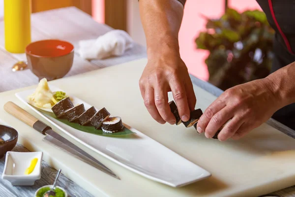 Mannelijke handen houd sushi rolls. — Stockfoto