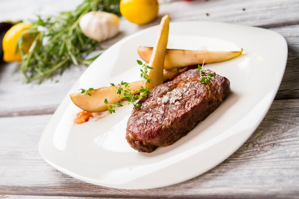 Коричневое мясо на белой тарелке
.