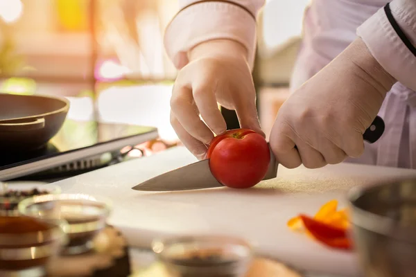 Hand med kniv skär tomat. — Stockfoto
