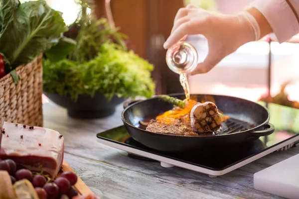 Bottle pours liquid on pan. — Stock Photo, Image