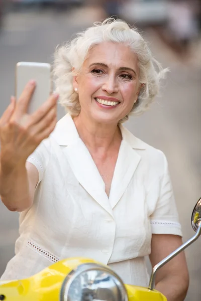 Smiling lady looks at phone. — Stock Photo, Image