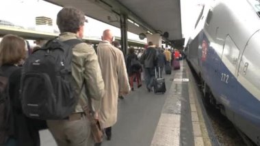 Tren platformu üzerinde yürüyen insanlar.