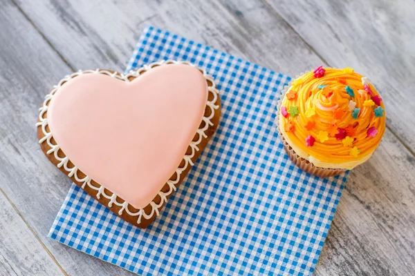 Hart van biscuit en oranje cupcake. — Stockfoto