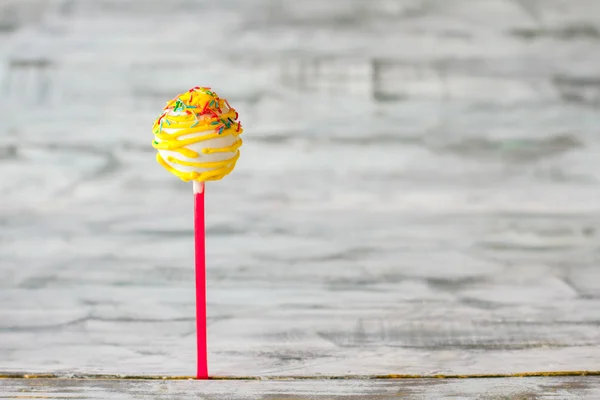 Yellow cake pop with sprinkles.