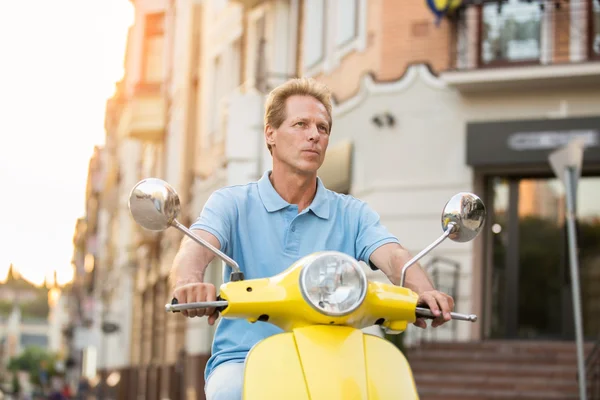 Mature man on yellow scooter.
