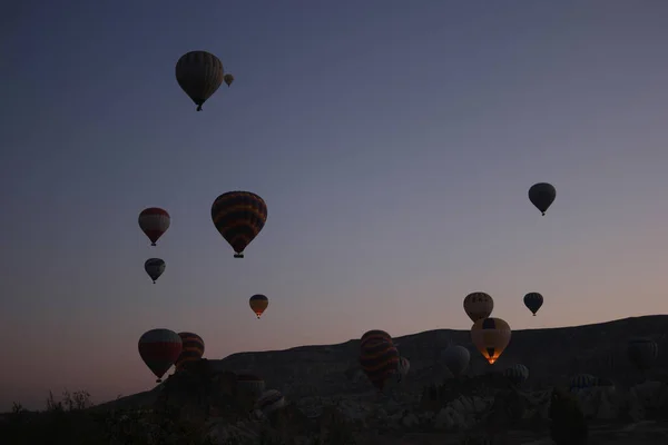 Hete lucht ballonnen vliegen in zonsondergang hemel boven de bergen. — Stockfoto