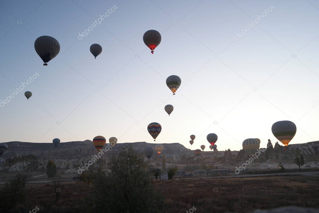 Hot air balloons flying over rocky landscape.