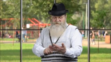 Cam tablet kullanan yaşlı sakallı adam..