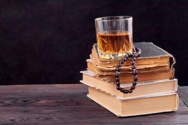 Bir yığın kitabın üzerinde bir bardak alkol..