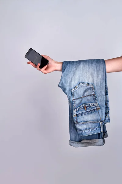 Żeńska ręka ze smartfonem i dżinsami. — Zdjęcie stockowe