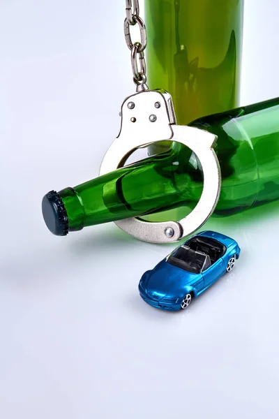 Schnapsflaschen mit Handschellen und Miniatur-Auto. — Stockfoto