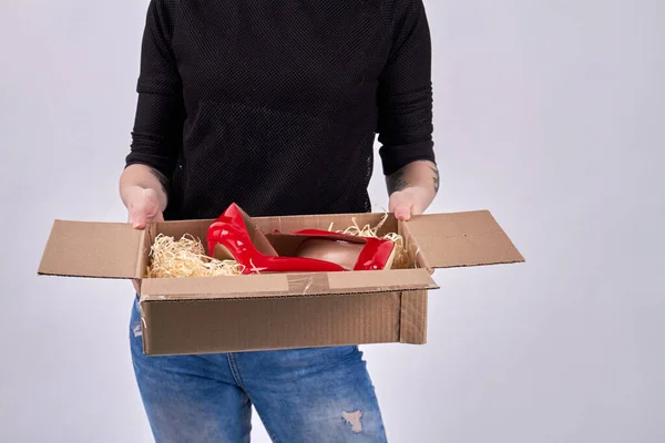 Portret van een meisje dat een pakje uitpakt met rode schoenen. — Stockfoto