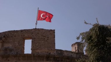 Rüzgarda dalgalanan Türk bayrağıyla tarihi bir kale..