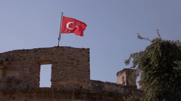 En forntida historisk fästning med turkisk flagga viftande i vinden. — Stockvideo