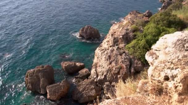 청록색 바닷물 위에 있는 바위 절벽 꼭대기의 모습. — 비디오