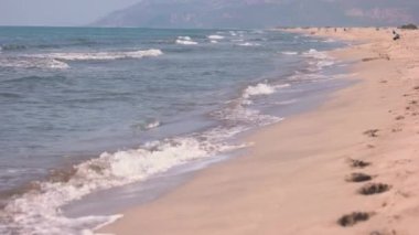 Kumlu sahildeki dalgalı denize yaklaş.
