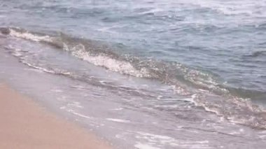 Kumsalda kıyıya vuran köpüklü deniz dalgalarını kapatın..