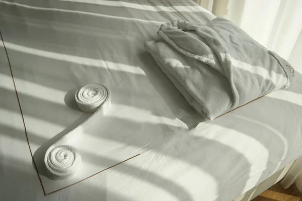 Gefalteter weißer Bademantel auf dem Bett im Hotelzimmer. — Stockfoto