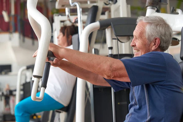 Entrenamiento de hombre mayor en la máquina de prensa en el club de gimnasio. —  Fotos de Stock