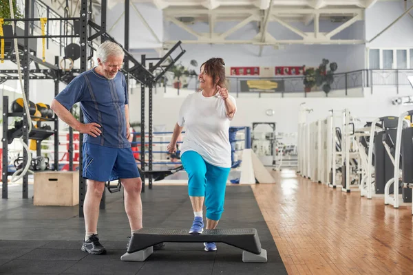 Spor salonunda egzersiz yapan neşeli yaşlı kadın..