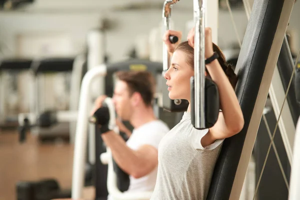 Mujer bastante delgada haciendo ejercicio en el pecho en el gimnasio. — Foto de Stock