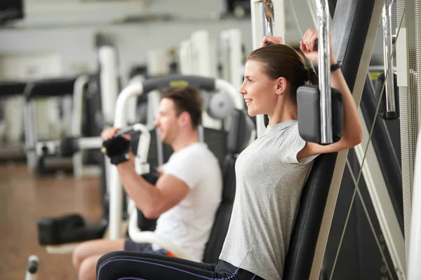 Pretty woman doing exercise on chest press. — Stock Photo, Image