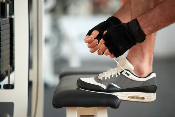 Homem amarrando sapatos esportivos antes do treino no ginásio. — Fotografia de Stock