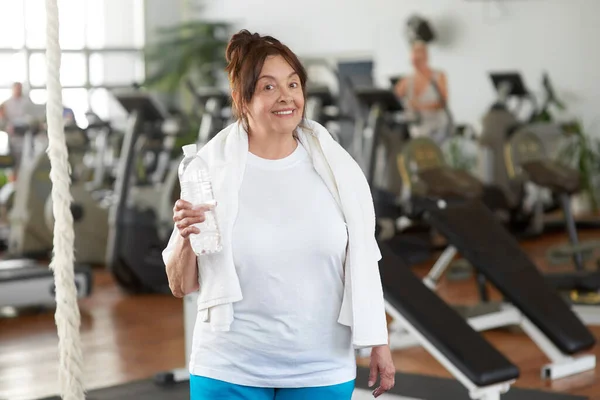 Senior woman holding bottle of water at gym. — Stock Photo, Image