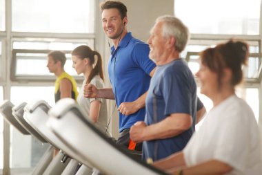Genç yakışıklı adam spor salonunda koşu bandı kullanıyor..