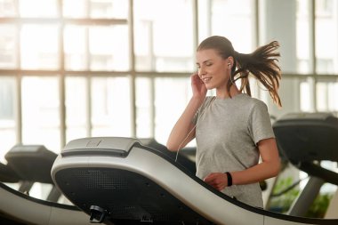 Koşu bandında koşan aktif genç bir kadın.