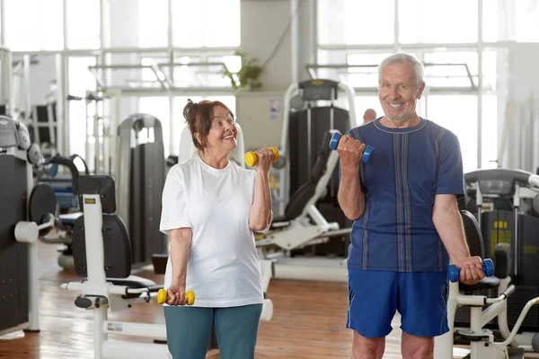 Senior caucasian couple exercising using dumbbells.