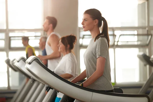 Vista lateral de la joven en la cinta de correr en el gimnasio. — Foto de Stock