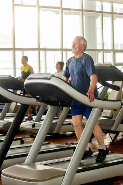 Hombre mayor entrenando sus piernas en el gimnasio. — Foto de Stock
