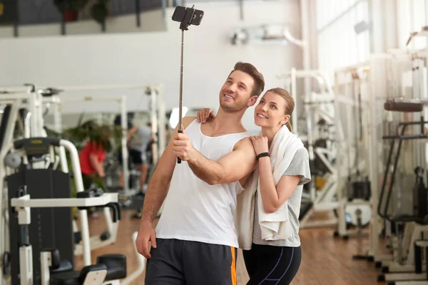 Pareja atlética usando selfie stick en el gimnasio. — Foto de Stock